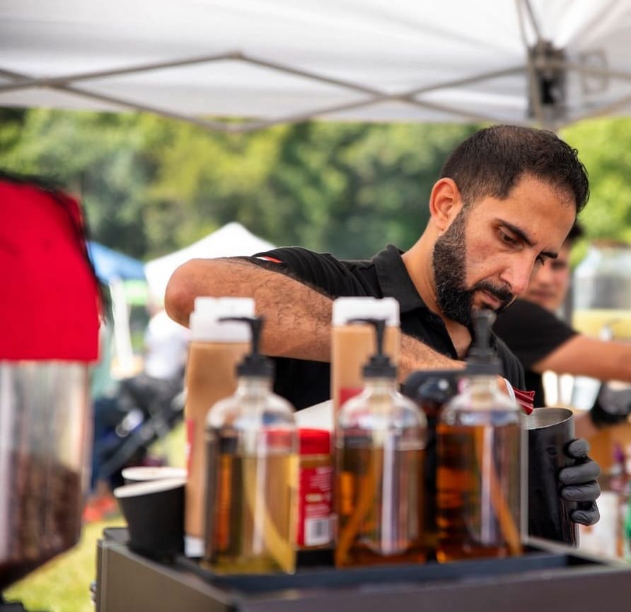 Coffee Malem founder Amro preparing a drink at an outdoor event coffee station.